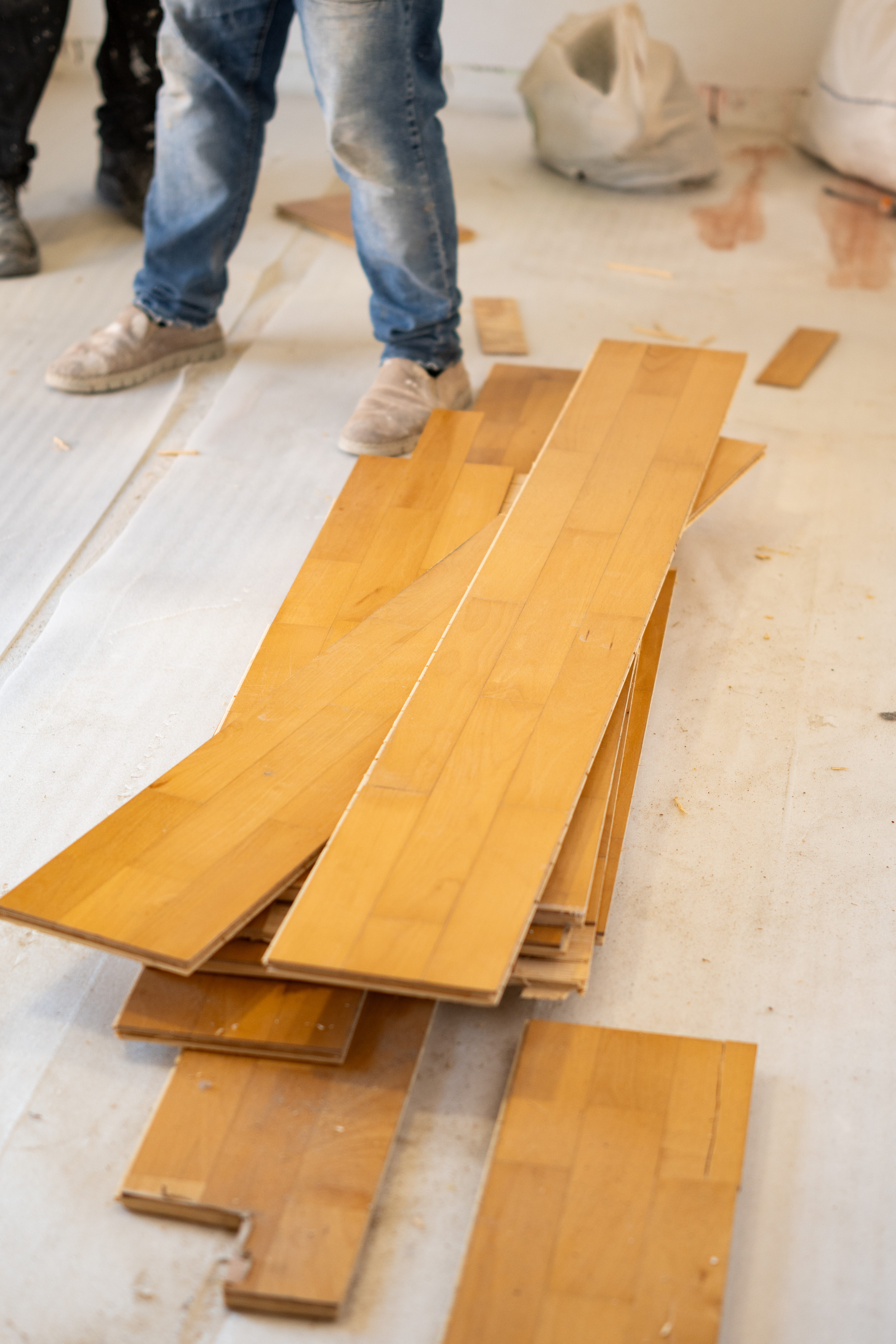 Worker installing new hardwood flooring during home renovation project