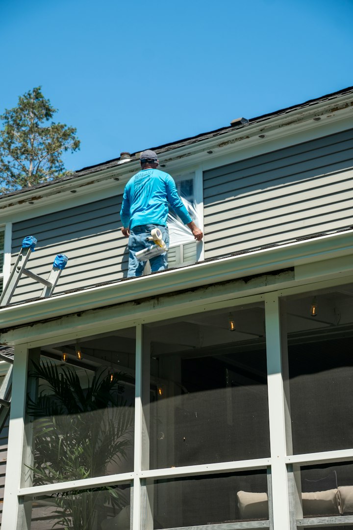 Professional roofer working on a residential clay tile roof, secured with a safety harness. Concept of home maintenance, construction safety, roofing work, and professional installation.