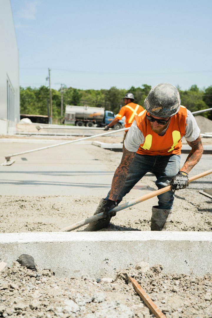 Construction worker in safety helmet and overalls applying spackle or plaster to a wall with a spatula tool, renovating a room